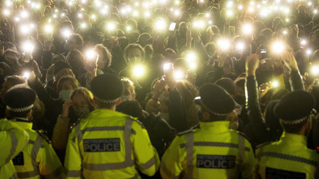 Line of police in front of crowd with telephone torches shining