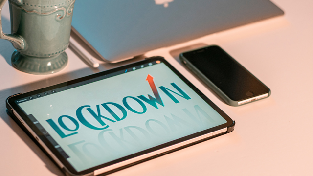 Desk with phone, tablet and cofffee cup - tablet has 'lockdown' message
