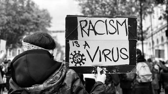Protestor carrying a 'racism is a virus' banner