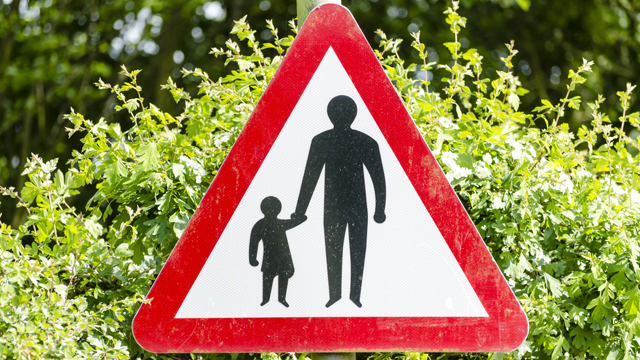 Road danger sign with adult and child holding hands