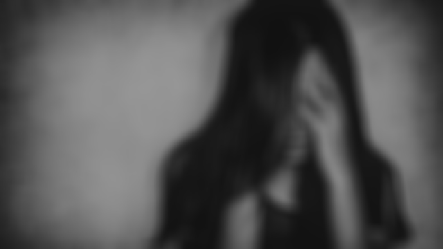 Blurred image of young woman with head in hands looking depressed