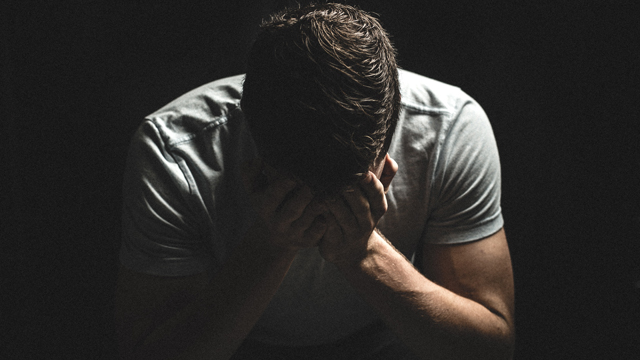 Depressed man with head in hands