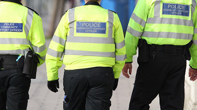 Three police officers walking away from camera outdoors