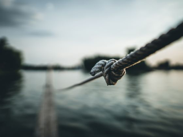 A close up of a knotted rope near a lake