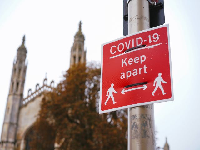 red sign on lampost with text COVID-19 Keep Apart