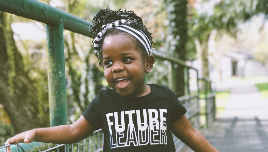 Young black girl smiling, wearing a t-shirt that reads Future Leader. Photograph by Kiana Bosman, capturedby_kiana