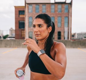 Woman wearing workout clothes and a smartwatch in front of a building