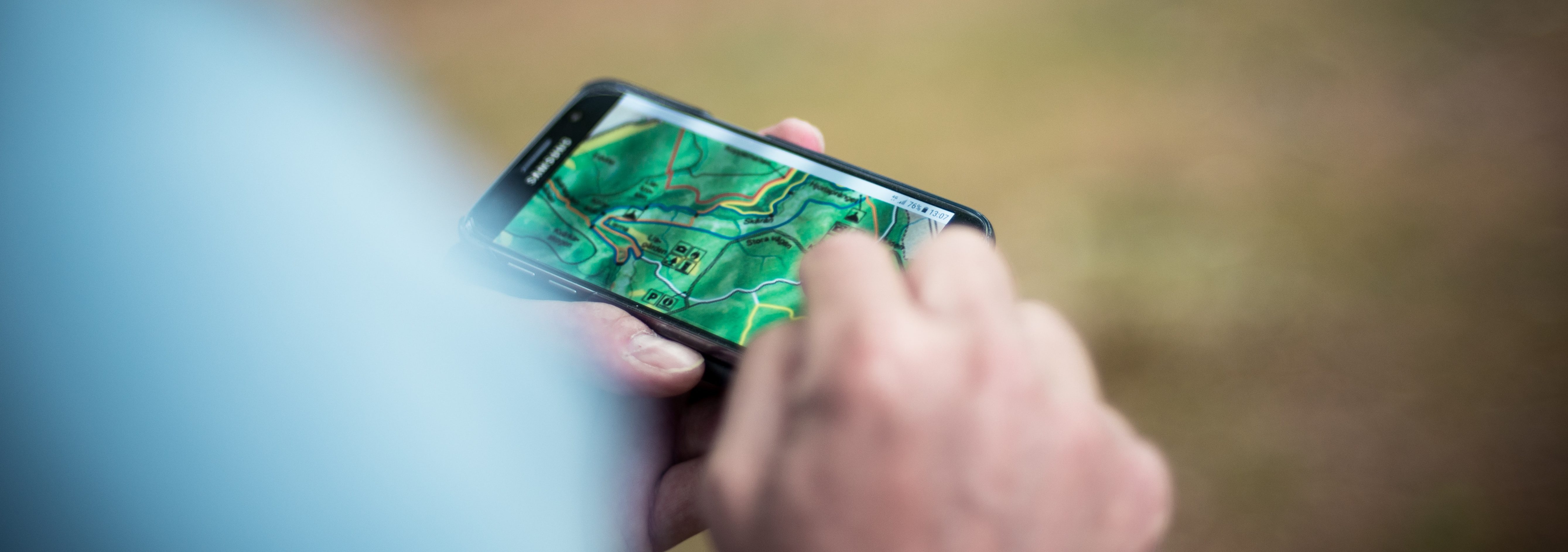 linda-sondergaard-oSvBeKi8vLA-unsplash Close up of hands holding a smartphone showing a map