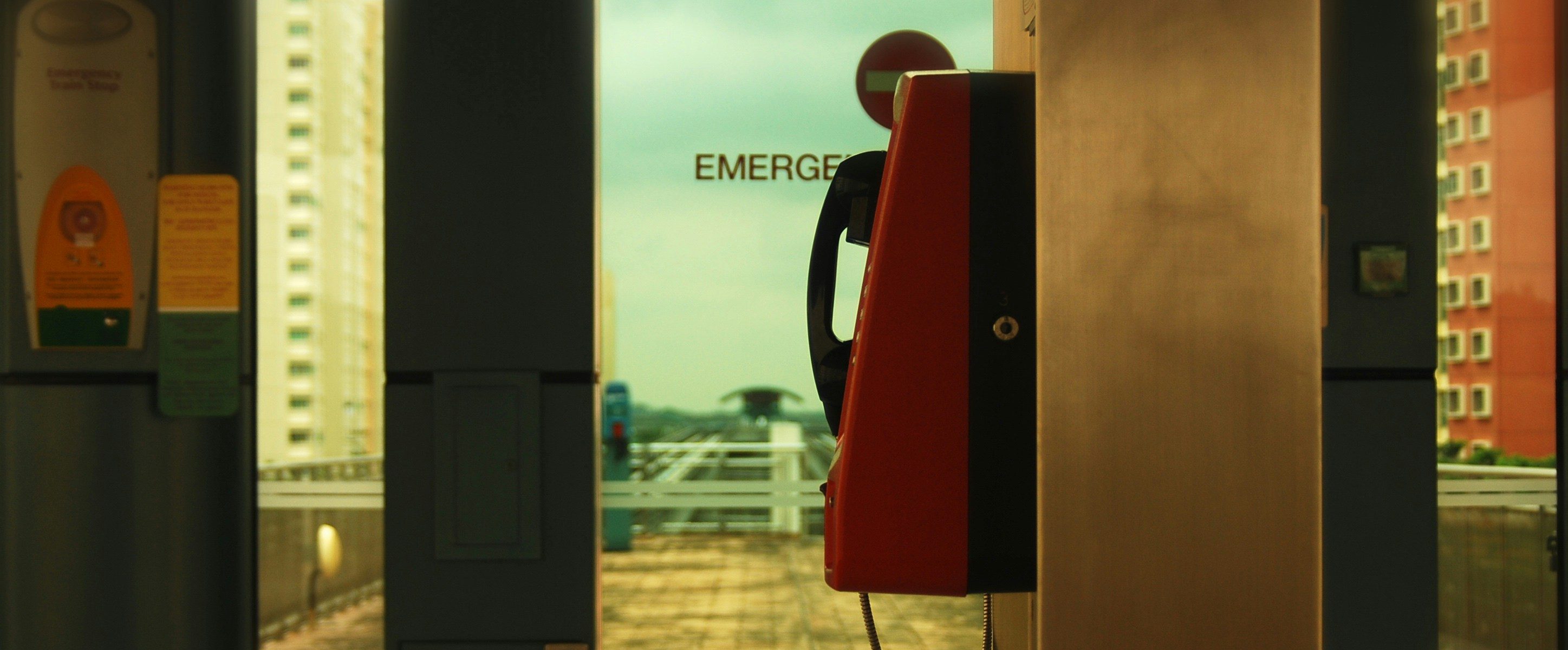 victor-he-8wOToN7KeQ4-unsplash Wall phone in front of a door labelled Emergency