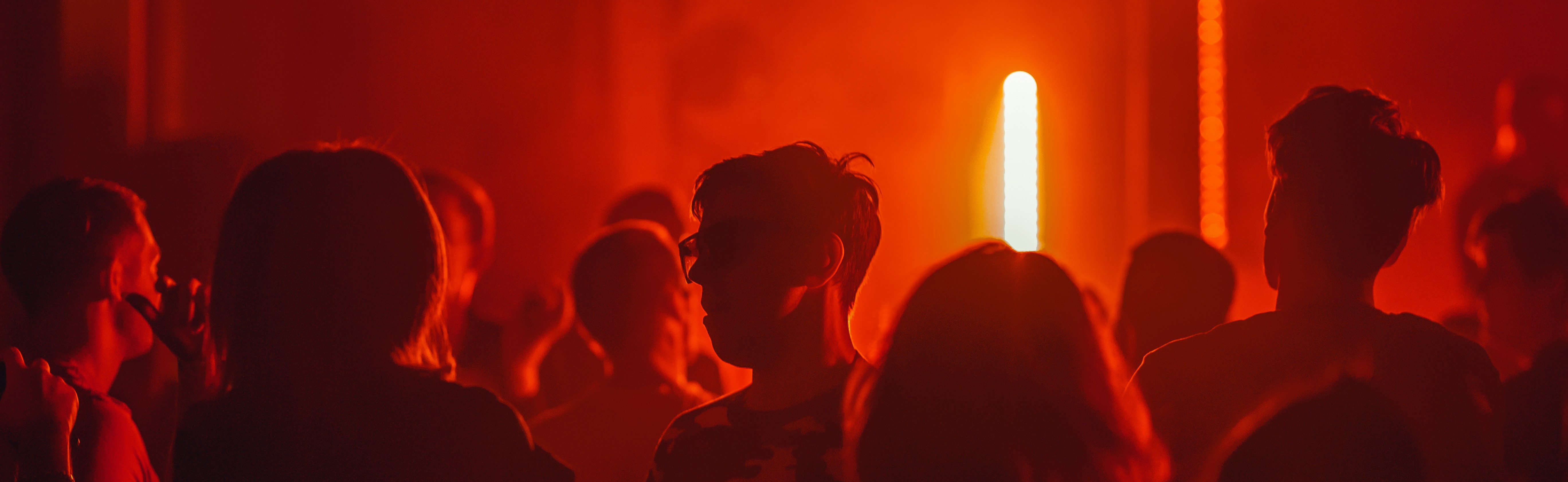 max-titov-9U8dZz8niS0-unsplash sihoutted figures in red strobe lighting
