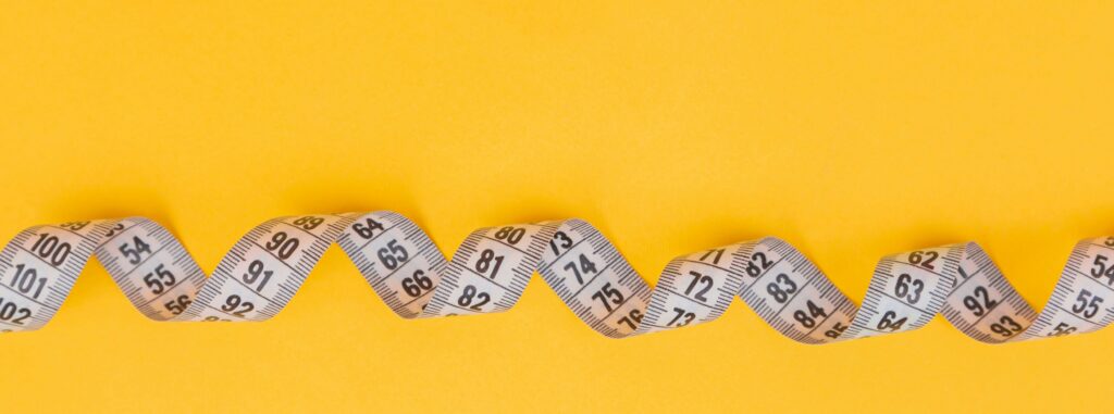 White measuring tape on a yellow background.